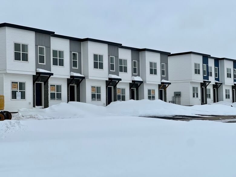 A row of townhouses is shown. They all have white and grey siding.