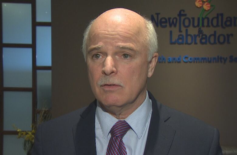 A middle-aged, bald man in a suit and a tie stands in the foyer of an office in the west block of the confederation building in St. John's, Newfoundland.