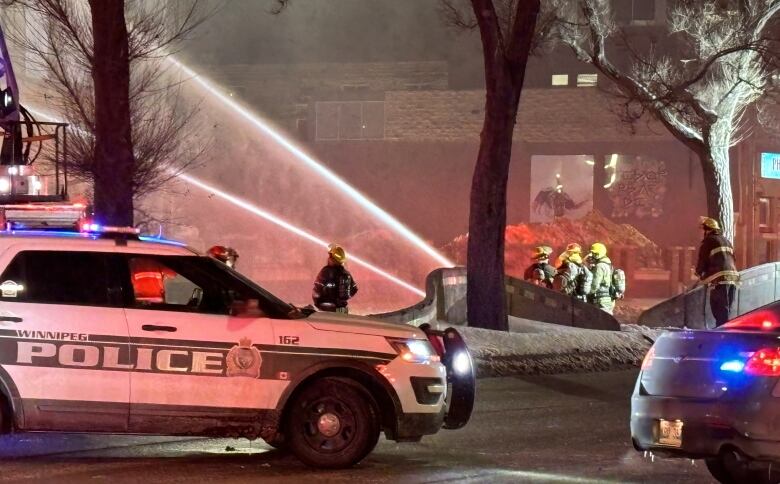 Firefighters direct their hoses upwards.