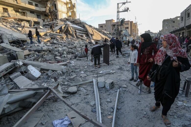 People walk through the rubble left after an airstrike on a building in Rafah, Gaza. 