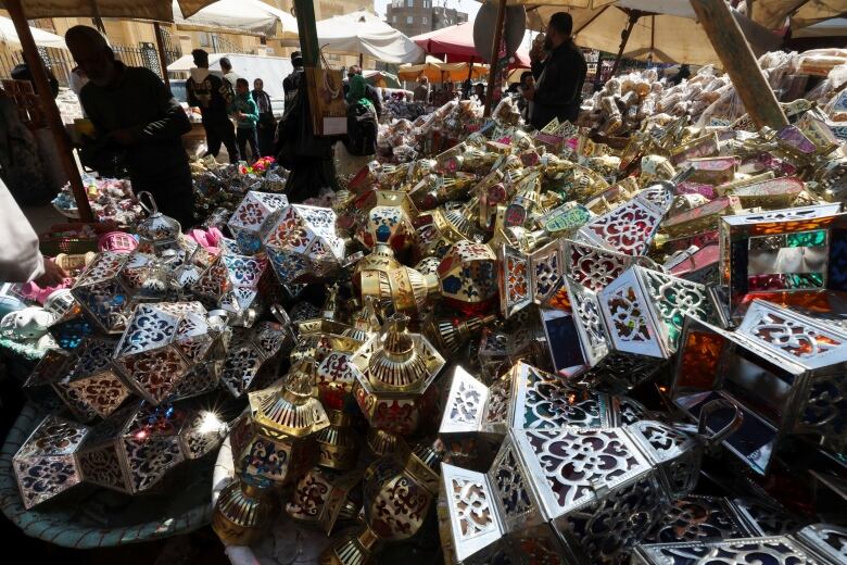 People survey  decorative lanterns piled up on display at a stall.