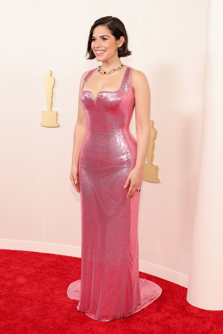 A woman wears a stylish pink dress during a red carpet event.