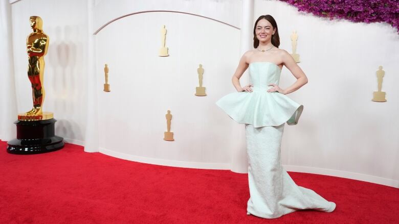 A woman puts her hands on her waist while posing for a photo at a red carpet event.