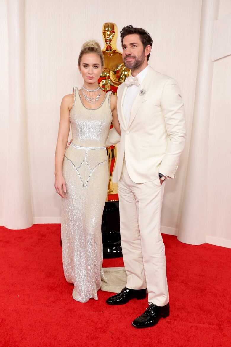 A woman and a man wear cream-coloured eveningwear during a red carpet event.