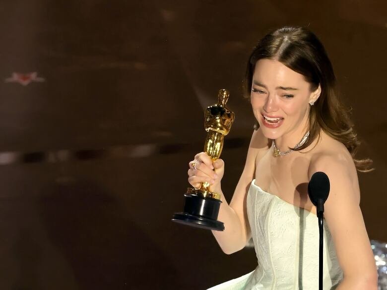 A woman holds a trophy.