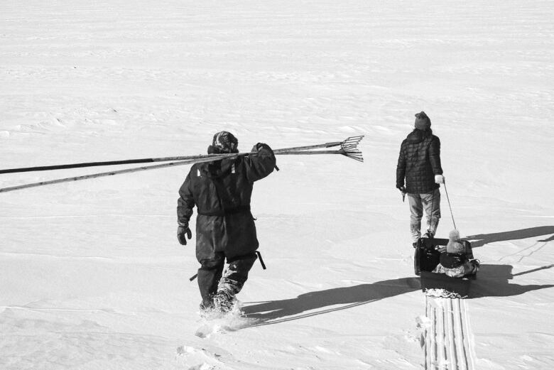 two men walking on the ice with gear