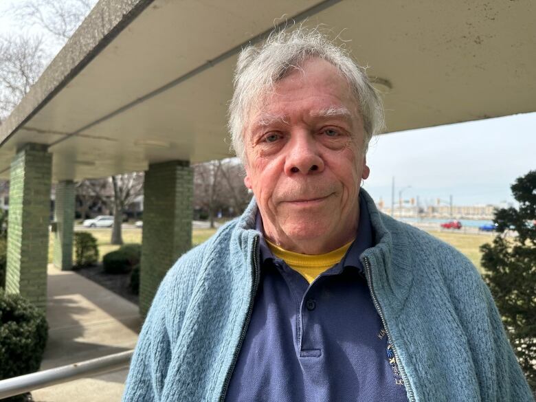 A man stands outside under a canopy. 