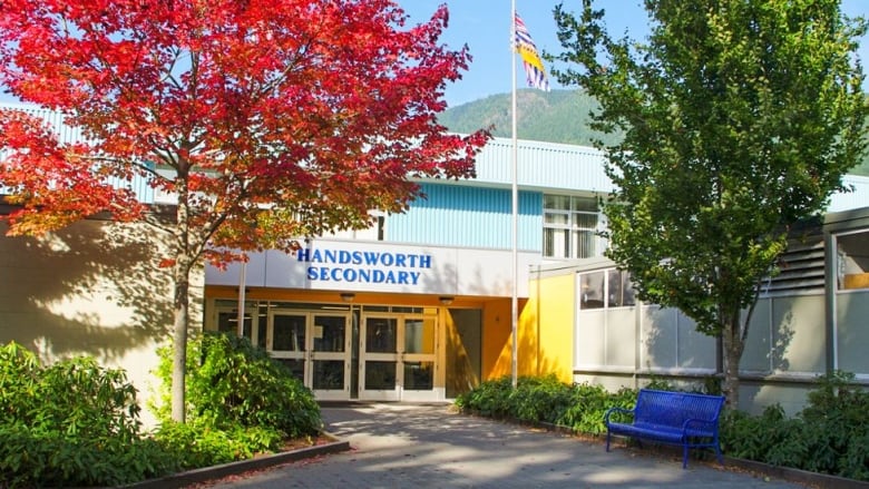 A school building on a sunny day is seen with a British Columbia provincial flag and the words 