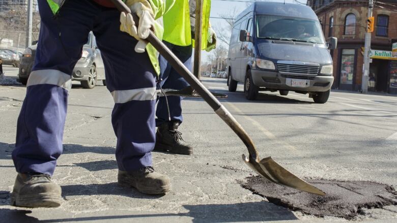 A city worker fills a pothole.