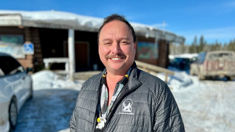 A smiling man stands outside a building on a winter's day.