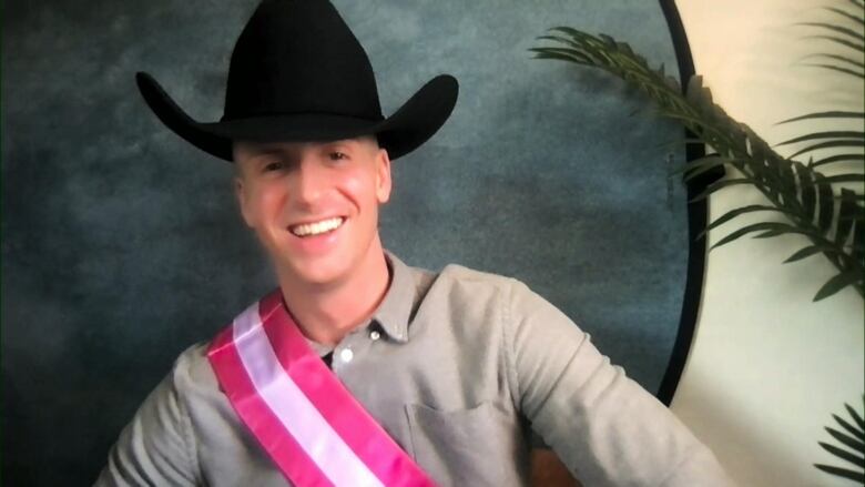 a man in a black hat, pink sash and button-up shirt