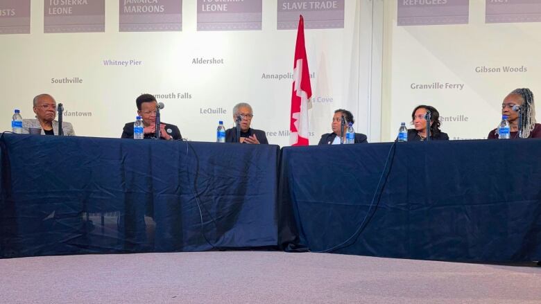 Six women sit at a panel table.