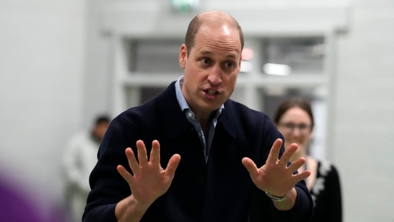 A man in a blazer holds up his hands