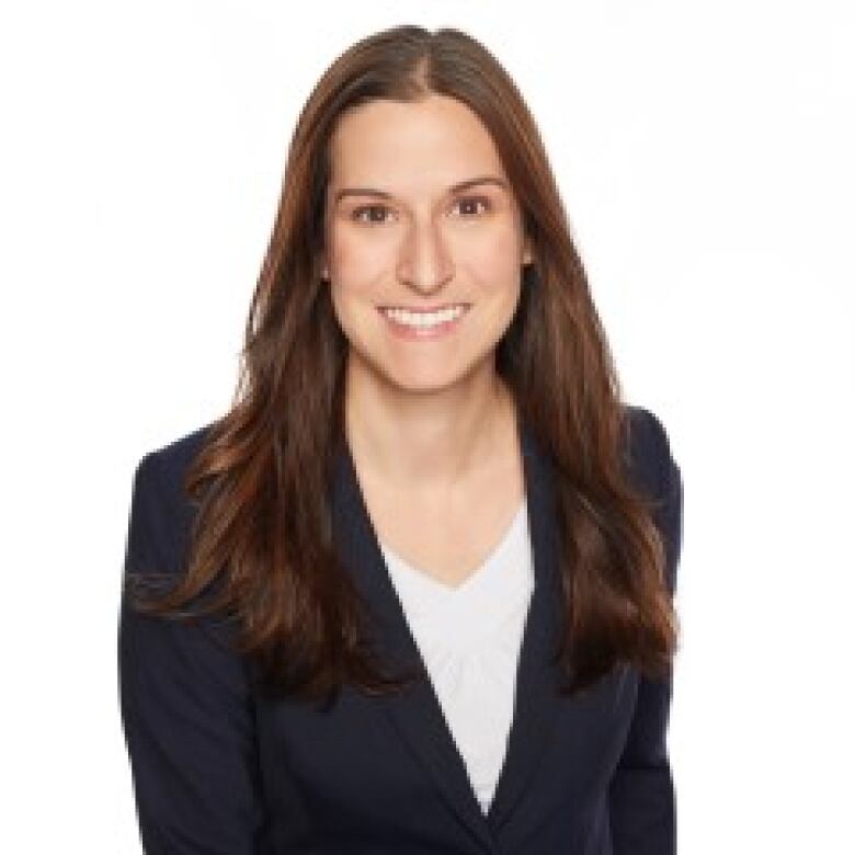 A headshot of a Caucasian woman with long brown hair wearing a blazer. 