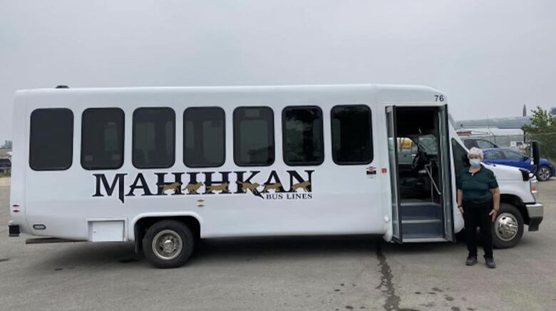 A woman stand in front of a bus.