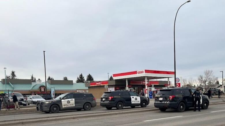 Police cars in front of a gas station.