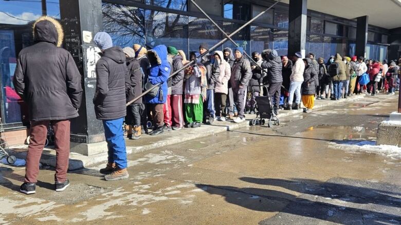 A long line of people in winter clothing wait outside to get into the Cuisines et vie collectives Saint-Roch food bank.