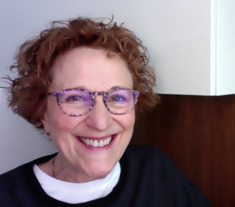 A woman with curly brown hair and glasses.