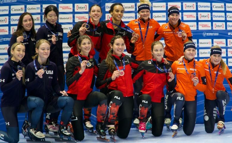 A group of woman pose with their medals dress in team colours.