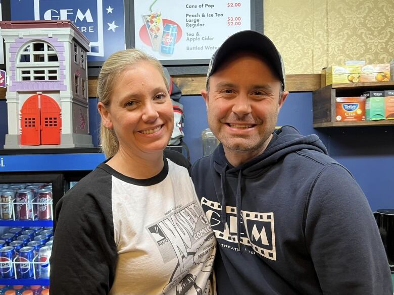 A smiling couple poses inside a movie theatre. 