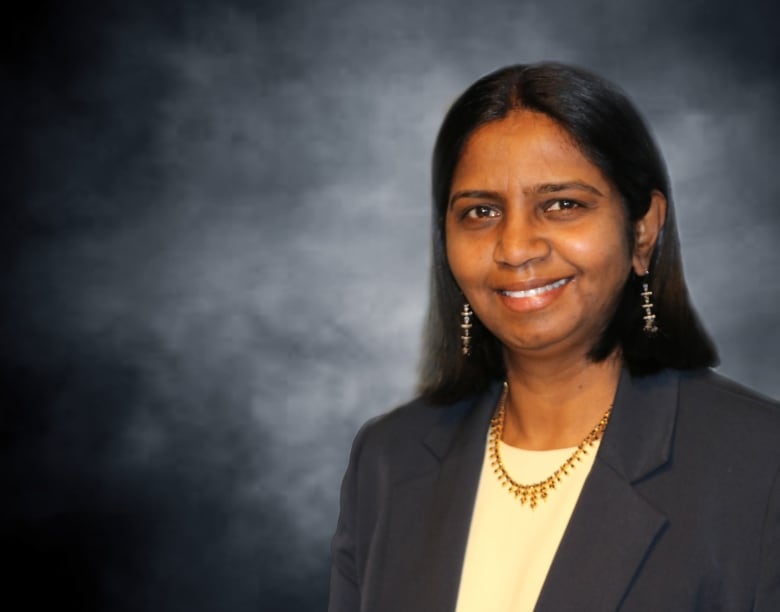 Shanthi Johnson poses for a photograph with a grey background.