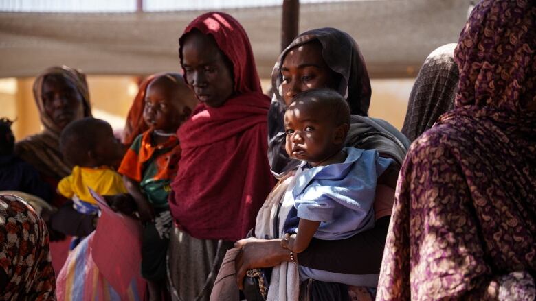 A group of women huddled close together, many holding babies.