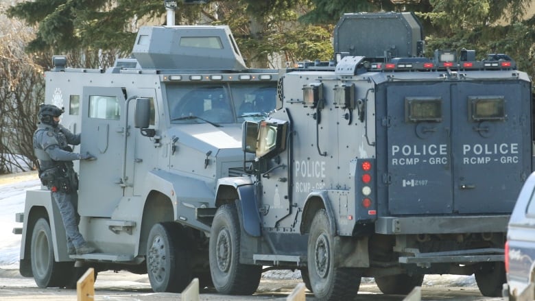 Calgary police and RCMP tactical team members keep watch on a house where shots were fired.  