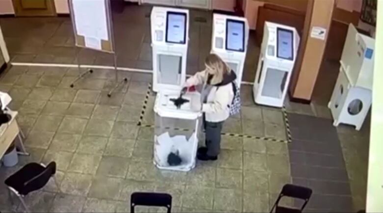 A woman pours green liquid into a ballot box.