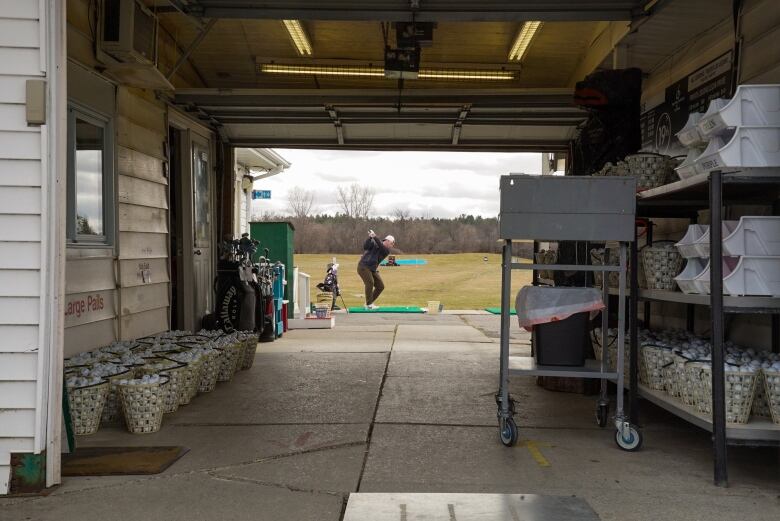 A golfer takes a swing at 19th Tee Driving range in Kanata. Seen through the entrance.