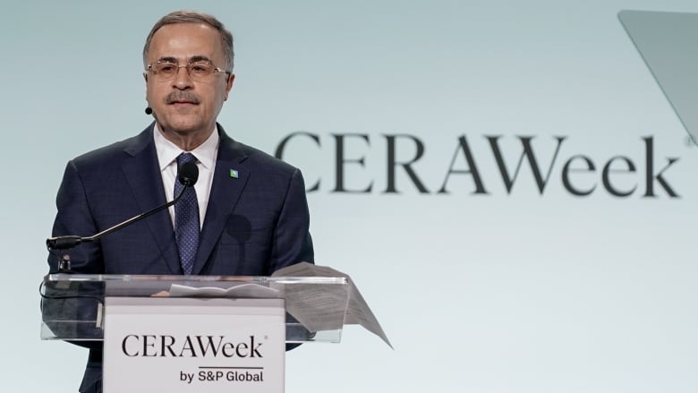 A man in a suit speaks at a podium.