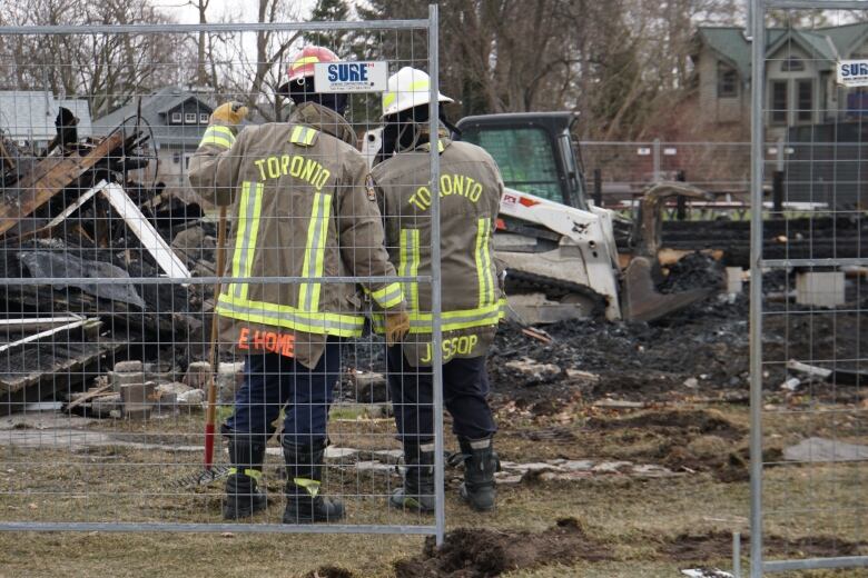 Two firefighters stand near the debris that is left after the fire early Sunday.