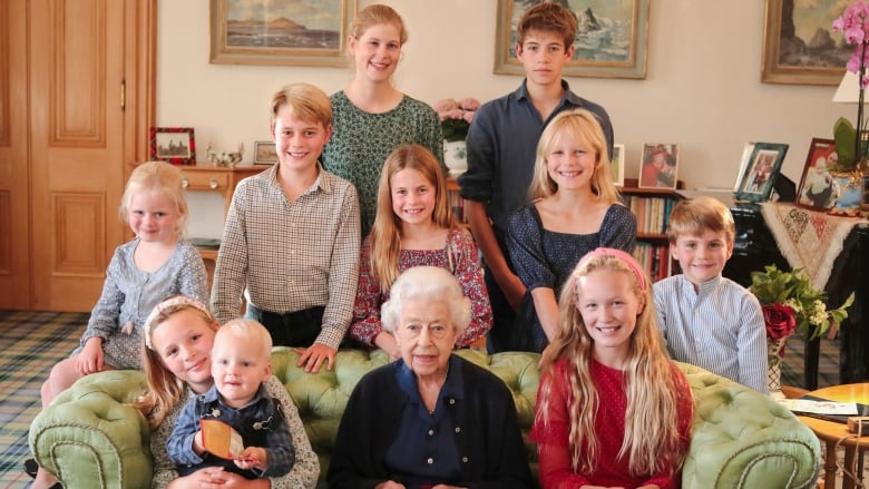 An older woman poses with 10 smiling children