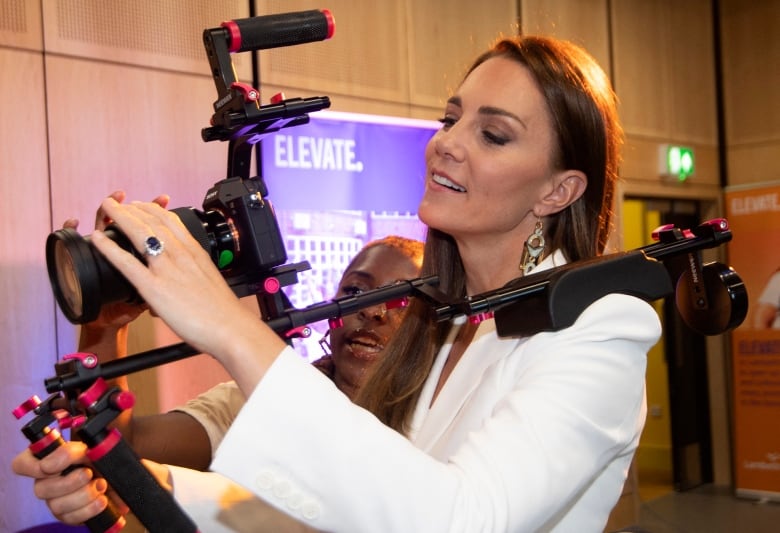 A woman with long brown hair holds a camera