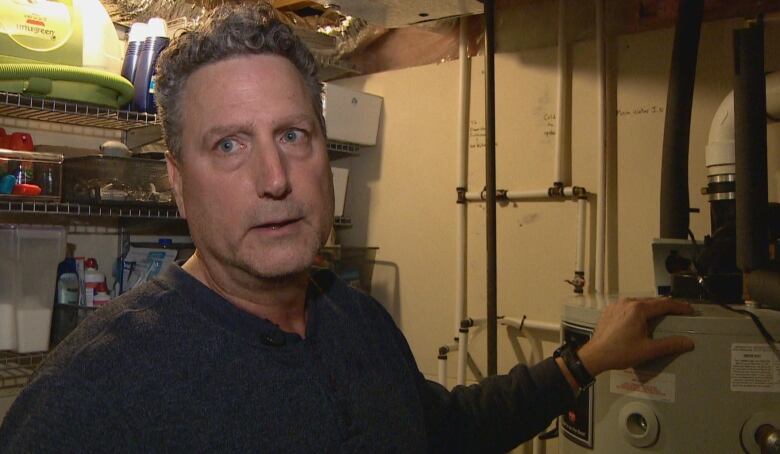 Jeff Ivan is in his basement, standing next to one of two hot water tanks. He is describing how his home is heated almost entirely by solar energy collected during the summer and used in the winter.