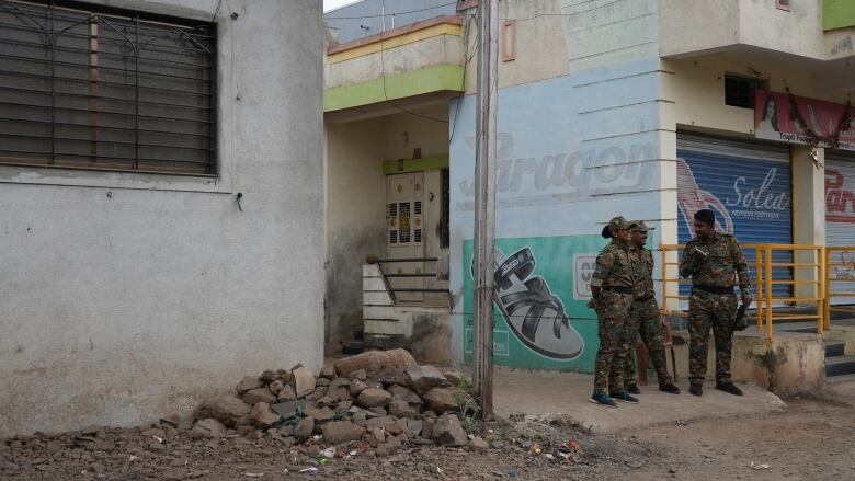 Police officers in camouflage uniforms stand outside a mosque. 