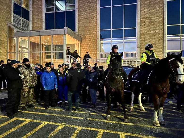 Police on horseback, other police and protesters around them. 