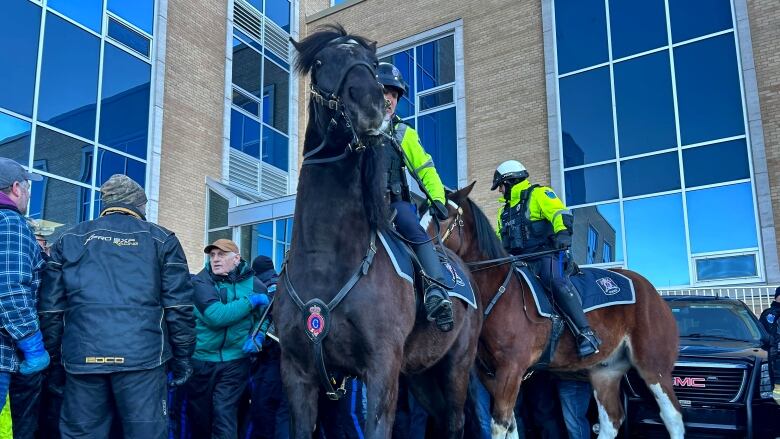 Police on horses and a crowd of protesters.