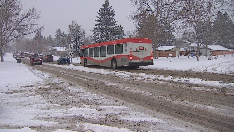 a snowy road with cars and a city bus.