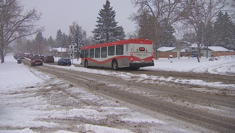 a snowy road with cars and a city bus.