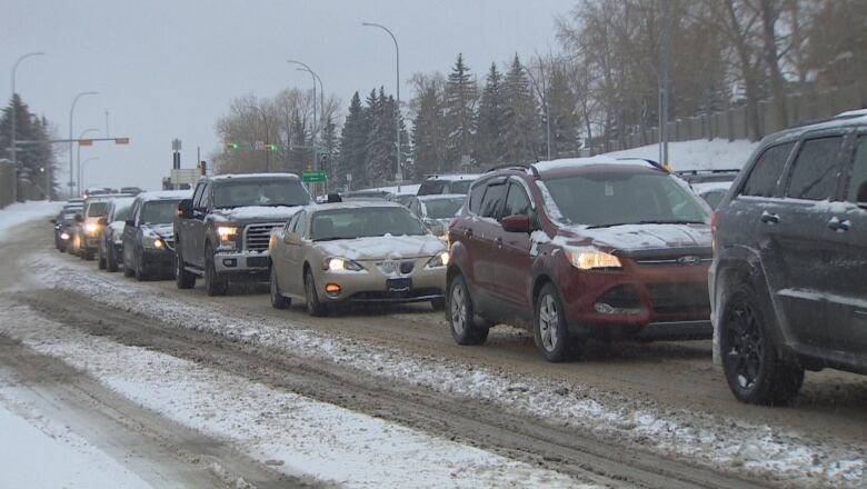 a lineup of cars on a snowy road.