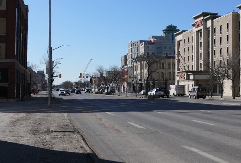 A street view with cars in the distance and buildings on both sides of the road.