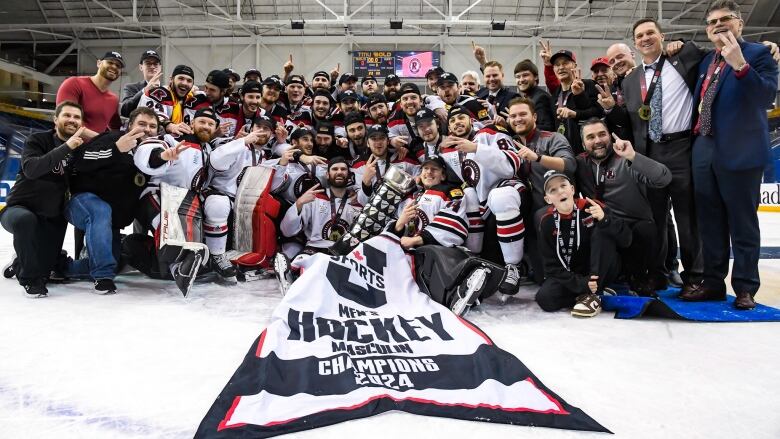 A hockey team poses with a championship banner 