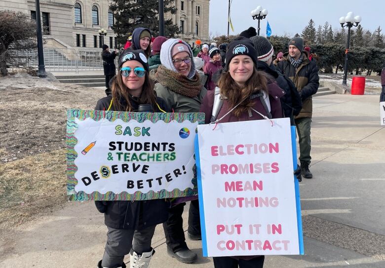 Teachers hold signs, including one that says 