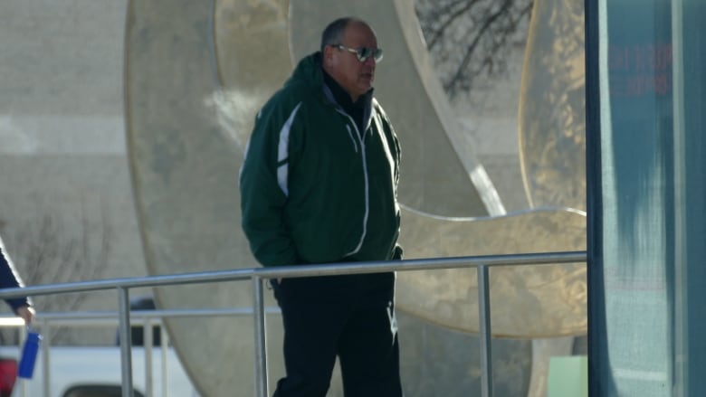 A man wearing sunglasses is pictured walking into a building.