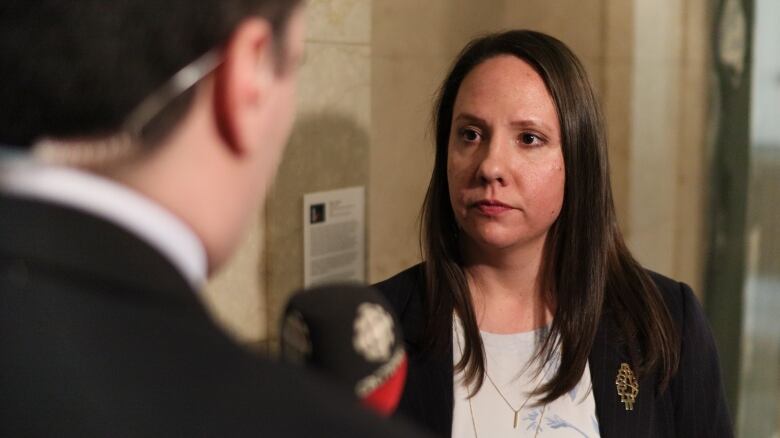 A woman wearing a black suit talking into a mike