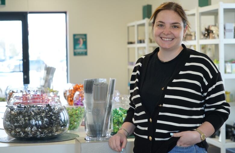 A woman stands beside a bowl of chocolate truffles. 