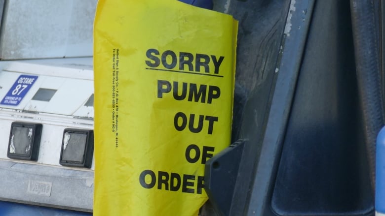 Close up of a gas pump with a yellow cover that says 