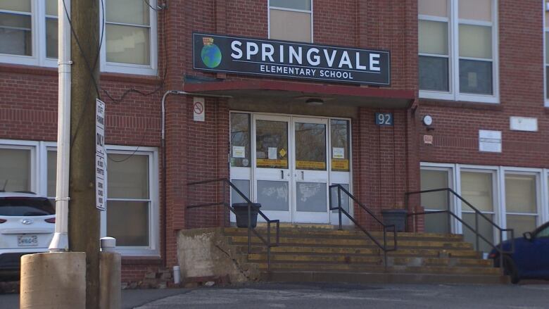 The front door of a school with concrete stairs leading up to it.