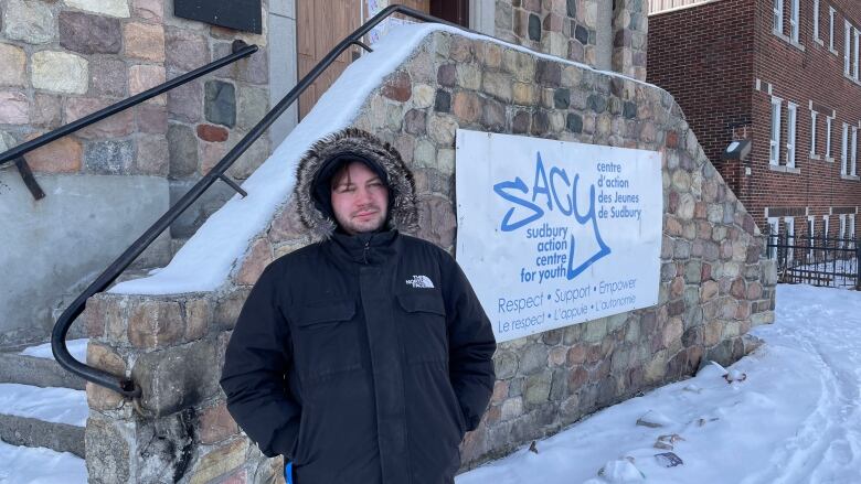 A young man standing outside with a dark winter jacket.