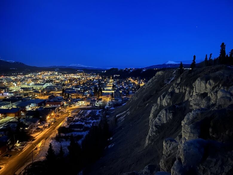 Looking down on a small city at night, from the top of a cliff.